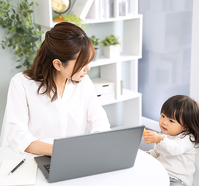 女性社員が子供を見ながら仕事している写真