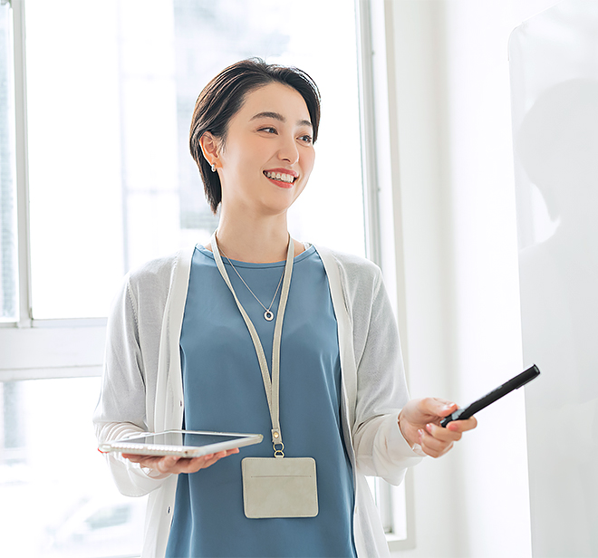 女性社員がホワイトボードの前で発言している写真